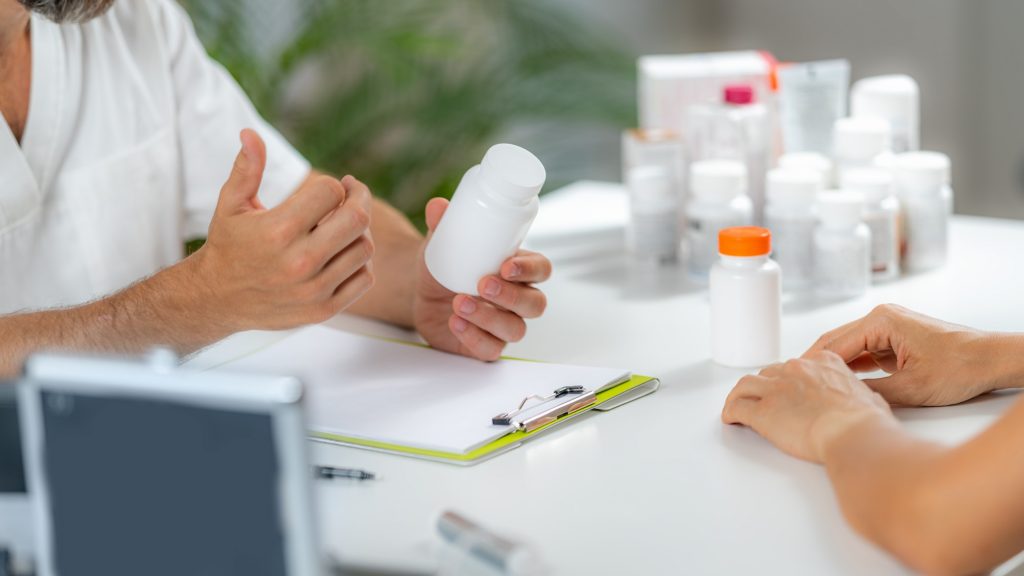 Quantum Medicine. Doctor Holding a Supplement Bottle, recommending supplements to a client.